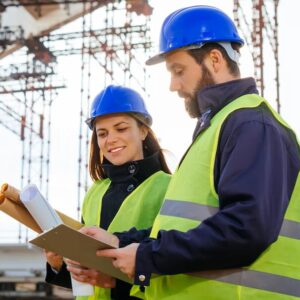 Teamwork-in-construction-industry---two-engineers-working-together-on-construction-site-with-blueprints-and-plans-645373486